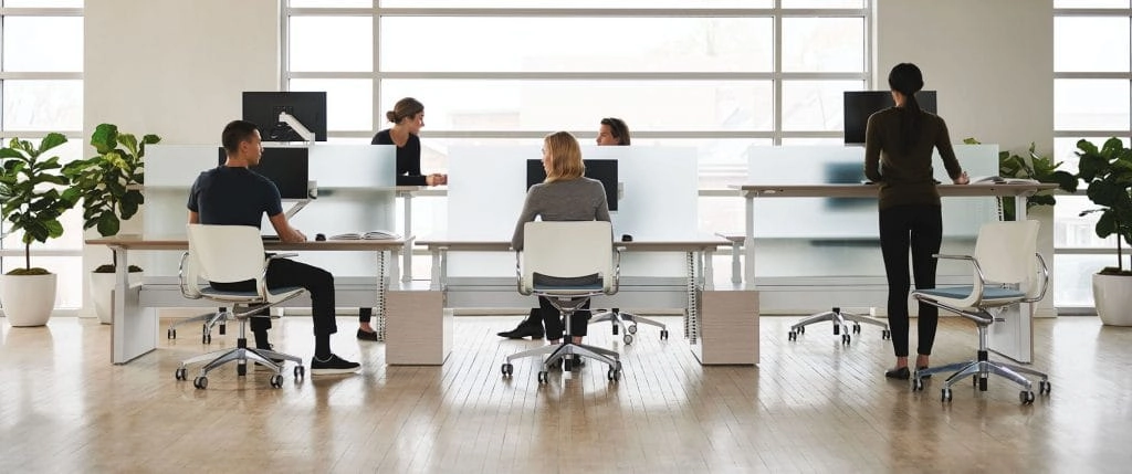 Modern open-plan office workspace with ergonomic chairs and shared desks